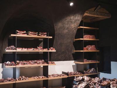 Regale mit verschiedenen Broten, dunkler Raum mit gewölbter Decke und warmem Licht.