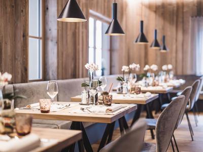 Restaurante acogedor con paredes de madera, mesas puestas y iluminación moderna.