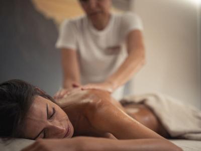 Frau erhält eine entspannende Rückenmassage in warm beleuchtetem, ruhigem Raum.