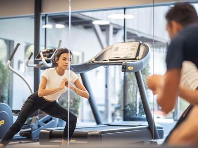 Frau beim Dehnen auf einer Matte im modernen Fitnessraum eines Hotels.