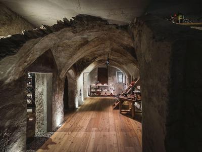 Alter Keller mit steinernen Bögen, Holzboden und gedämpftem Licht, rustikal und atmosphärisch.
