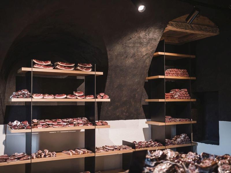 Regale mit verschiedenen Broten, dunkler Raum mit gewölbter Decke und warmem Licht.