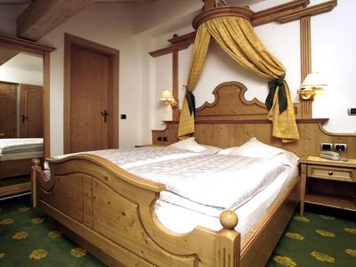 Holz-Doppelbett mit gelbem Baldachin in gemütlichem Hotelzimmer mit grütem Teppich.