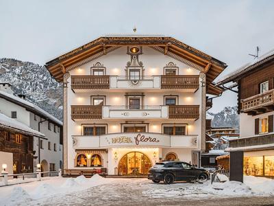 Alpines Hotelgebäude mit drei Etagen, hell erleuchtet und umgeben von Schnee und Bergkulisse.