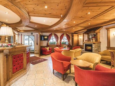 Gemütlicher Hotel-Loungebereich mit Holzmöbeln, Kamin und bunten Sesseln.