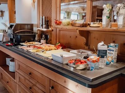 Buffet mit Brotauswahl, Milch und Müsli in gemütlichem Restaurant mit Holzmöbeln.