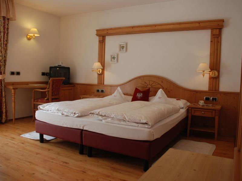 Gemütliches Schlafzimmer mit Doppelbett, Holzmöbeln und warmem Licht an den Wänden.