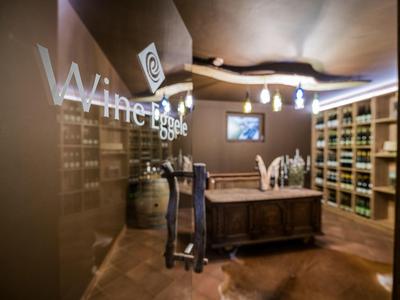 Moderner Weinkeller mit Holzregalen, Theke, Weinfass und dekorativer Beleuchtung.