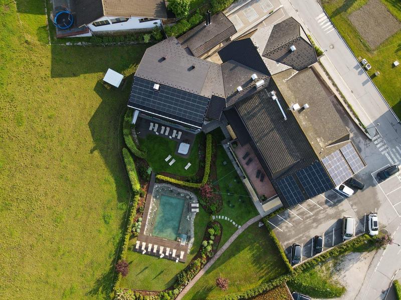 Luftaufnahme eines Hauses mit Solarpanels, Garten, Swimmingpool und angrenzendem Feld.