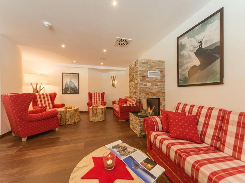 Gemütlicher Wohnzimmerbereich mit karierten Sofas, roten Sesseln, Holzboden und Wandbildern.