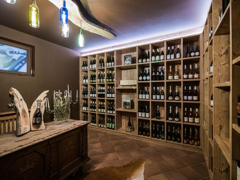Weinkeller mit Holzregalen voller Flaschen, rustikaler Kommode und stimmungsvoller Beleuchtung.