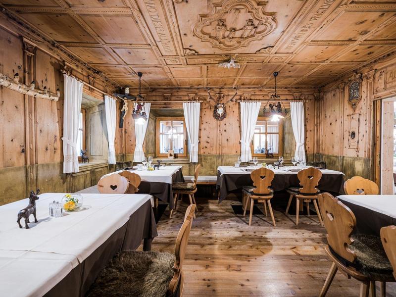 Gemütlicher Gastraum mit Holztäfelung, geschnitzten Stühlen und weißen Tischdecken.