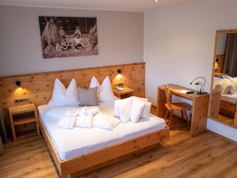 Gemütliches Schlafzimmer mit Holzbett, Nachttischen, Schreibtisch, Spiegel und hölzernem Boden.