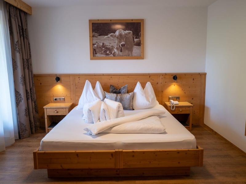 Gemütliches Schlafzimmer mit Holzbett, weißen Kissen, Holzpaneel und zwei Nachttischen.