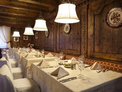 Gemütlicher Essraum mit Holzwänden, langem Tisch, weißen Stühlen und gedeckten Plätzen.