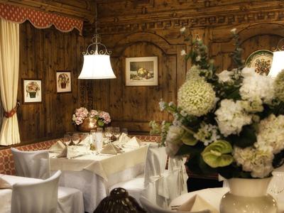 Gemütlicher Gastraum mit Holzwänden, weißen Blumen und gedeckten Tischen im traditionellen Stil.
