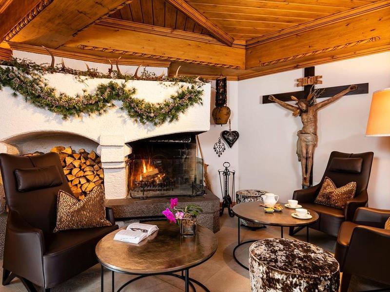 Gemütliche Sitzecke mit Kamin, zwei Sesseln, Holztisch und dekorativen Elementen in warmem Licht.