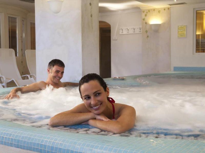 Zwei Personen entspannen in einem sprudelnden Whirlpool mit hellem, fließendem Wasser.