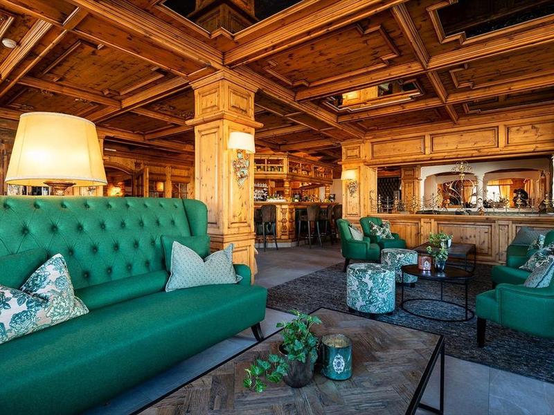 Gemütliches Wohnzimmer mit grünem Sofa, Holztäfelung und warmem Licht.