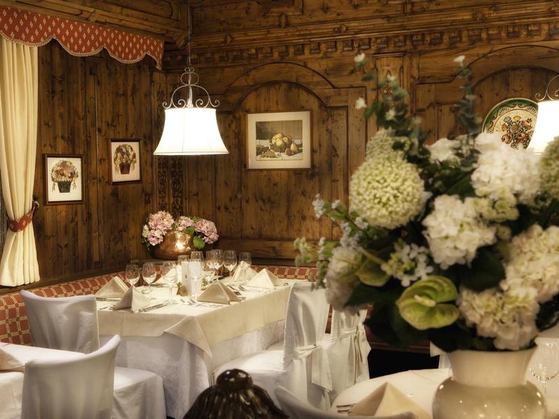 Gemütlicher Gastraum mit Holzwänden, weißen Blumen und gedeckten Tischen im traditionellen Stil.