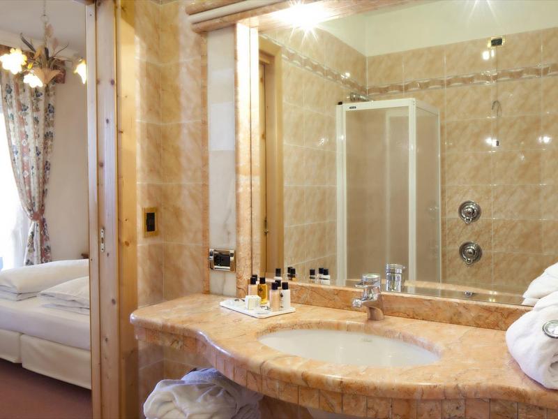 Modernes Badezimmer mit großem Spiegel, Marmorwaschbecken und Blick ins Schlafzimmer.