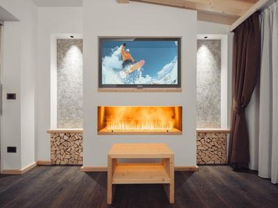 Modernes Wohnzimmer mit Kamin, Fernseher und Holzdekor in warmen Farben.