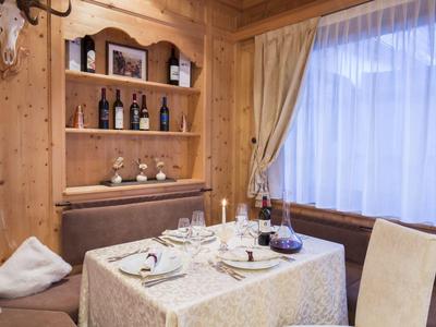 Gemütlicher Essbereich mit Holzwänden, gedecktem Tisch und Fenster mit Vorhängen.