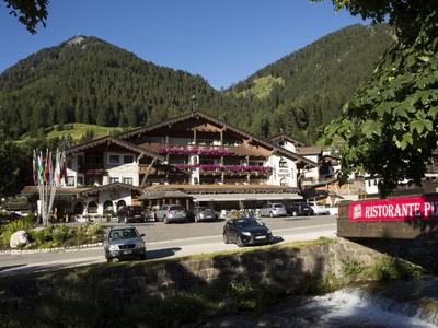 Ein Hotel in den Bergen mit Holzbalkonen und einer Terrasse, umgeben von Bäumen und Bergen.