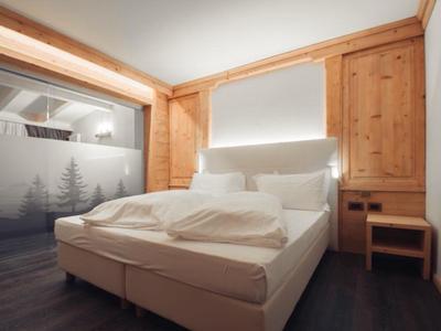 Modernes Hotelzimmer mit Doppelbett, Holzwänden und gedämpfter Beleuchtung.
