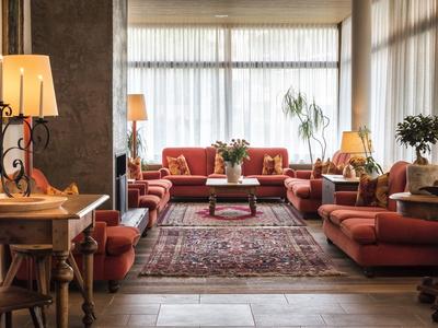 Gemütlicher Wohnraum mit roten Sofas, Teppich, Holzmöbeln und warmem Lampenlicht.