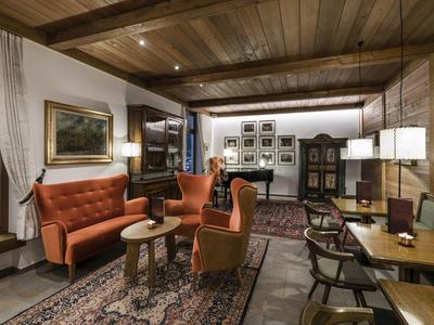 Gemütliches Wohnzimmer mit Holzdecke, roten Sesseln, Holzmöbeln und Teppich auf Holzboden.