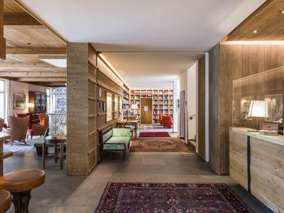 Heller Eingangsbereich mit Holzmöbeln, Sitzbank, Teppichen und Bücherregalen an den Wänden.