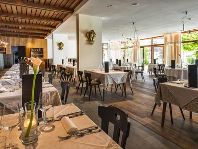 Helles Restaurant mit gedeckten Tischen, Holzboden, Stühlen und großen Fenstern für Tageslicht.