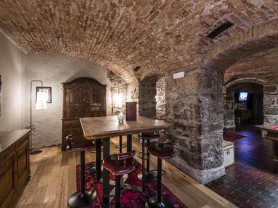 Historischer Gewölbekeller mit Holzmöbeln, Steinwänden und gedämpfter Beleuchtung.