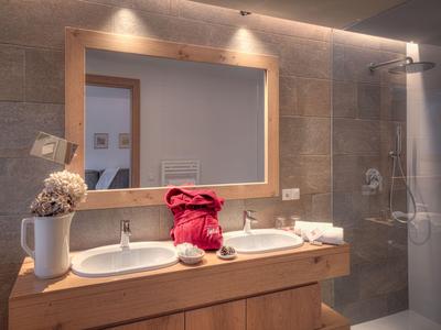Modernes Hotelbadezimmer mit Doppelwaschbecken, großem Spiegel und begehbarer Dusche.