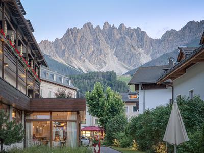 Hotelanlage mit Blick auf felsige Bergspitzen und Holzgebäude im Vordergrund.