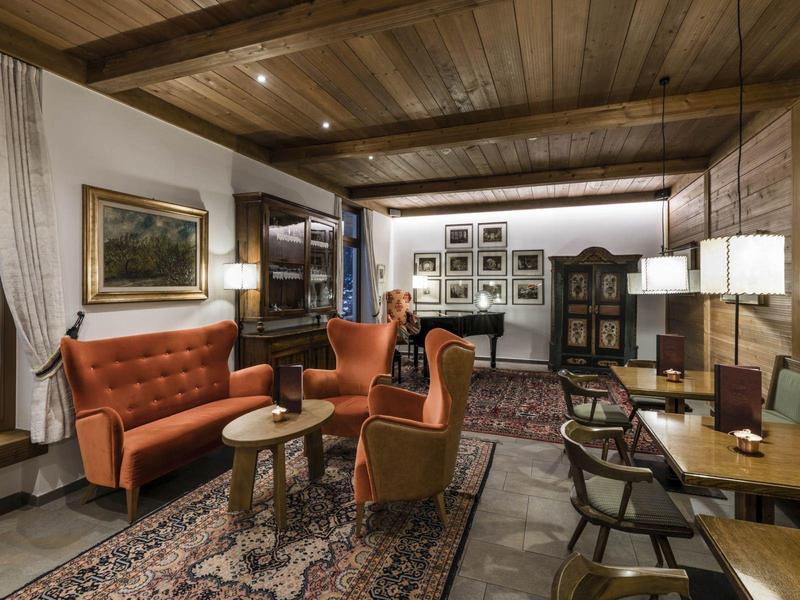 Gemütliches Wohnzimmer mit Holzdecke, roten Sesseln, Holzmöbeln und Teppich auf Holzboden.