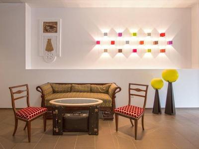 Area salotto moderna con divano, due sedie e tavolo davanti a decorazione murale illuminata