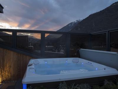 Vasca idromassaggio su una terrazza con vista sulle montagne al crepuscolo.