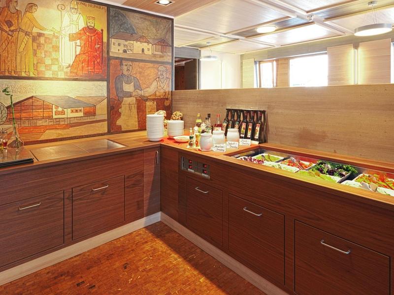 Innenecke einer modernen Küche mit Holzschränken, Arbeitsplatte und großem Wandbild.