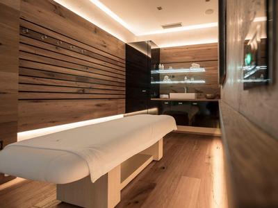 Sala massaggi moderna con pannelli in legno e lettino bianco in un'atmosfera rilassata.