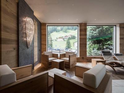 Area lounge accogliente con mobili in legno e grandi finestre con vista sulle montagne.