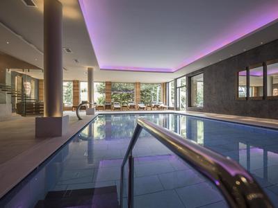Piscina interna moderna con canale d'acqua e illuminazione a soffitto indiretta in un hotel.