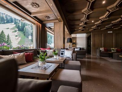 Area lounge elegante in hotel con comodi posti a sedere e finestre panoramiche con vista sulle montagne.