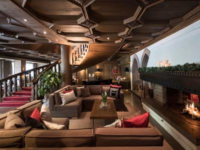 Ampia e accogliente lounge d'hotel con camino, divani e soffitto curvo in legno.