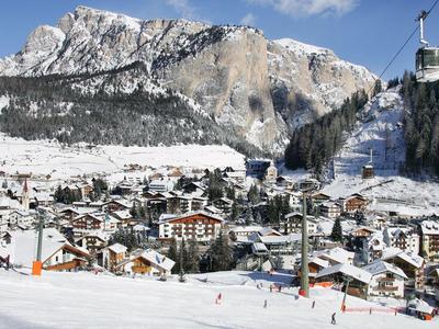 Villaggio invernale con area sciistica sotto montagne innevate e funivia sullo sfondo