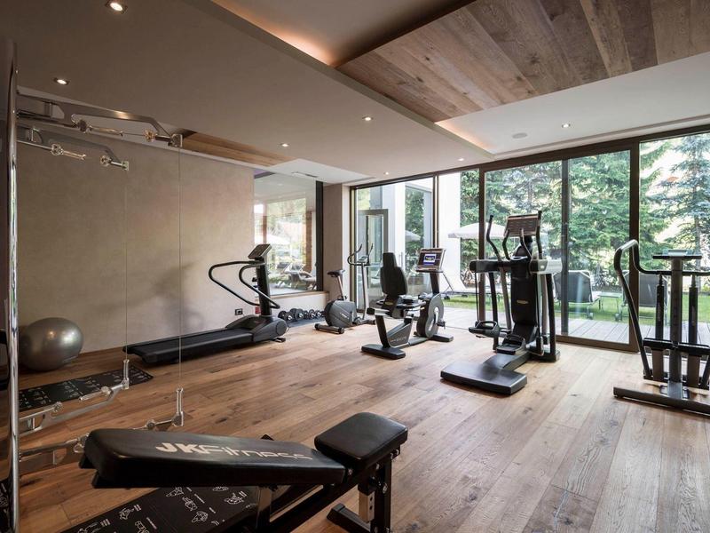 Palestra luminosa con attrezzature moderne e grandi finestre con vista su alberi verdi.