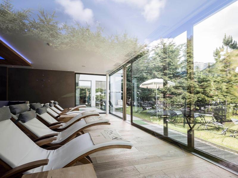 Comode poltrone relax in una stanza luminosa con grandi finestre di vetro che si affacciano su un giardino.