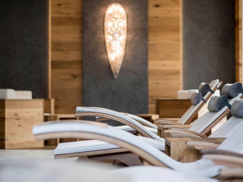 Fila di lettini bianchi davanti a pareti in legno in un'area relax dell'hotel.