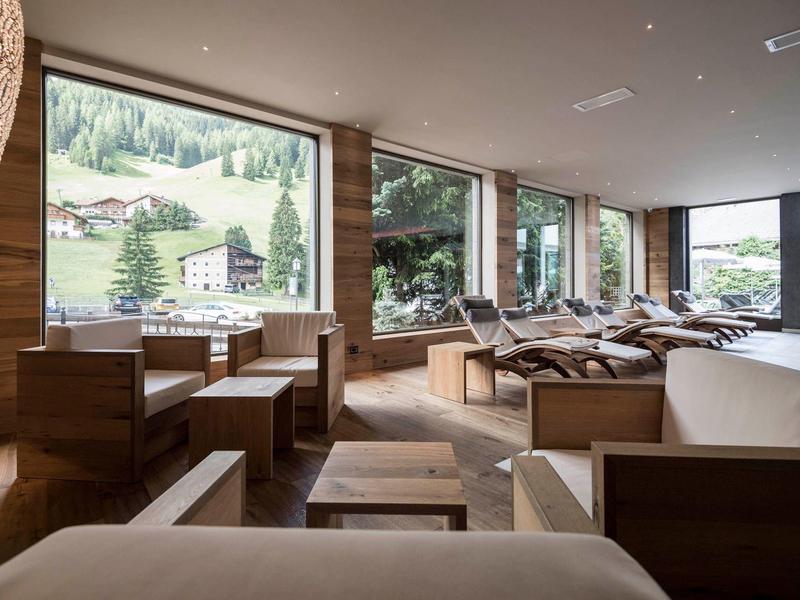 Accogliente zona lounge dell'hotel con mobili in legno e finestre panoramiche con vista sulle montagne.